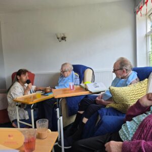Residents enjoying a live sing-along as a performer sings with a microphone during an afternoon activity.