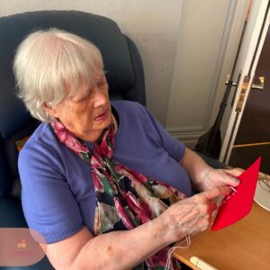 Resident concentrating on weaving colourful yarn through a felt craft board.