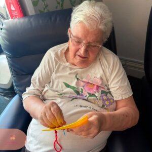 Resident enjoying a colourful stitching craft activity with focused attention.