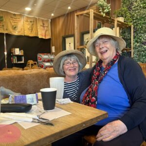 Two smiling residents enjoying drinks together at a café.