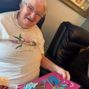 Elderly resident displaying a leaf painting.
