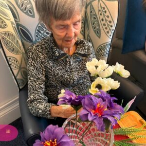 Elderly woman holding colourful flowers.