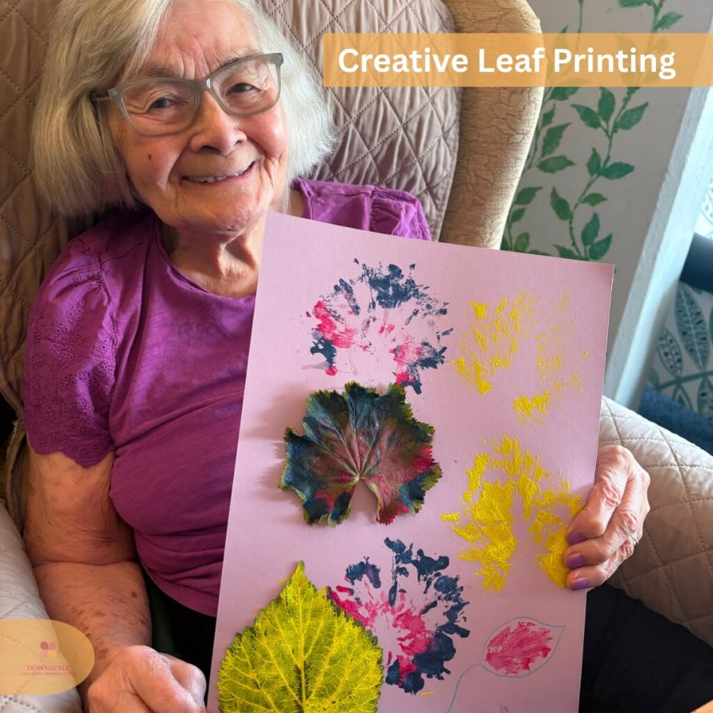 Resident smiling while displaying her leaf-print artwork.