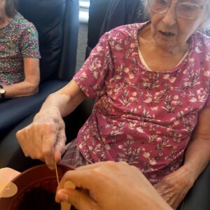 Elderly resident planting seeds with support.
