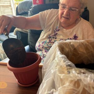 Elderly resident planting soil in a flower pot.