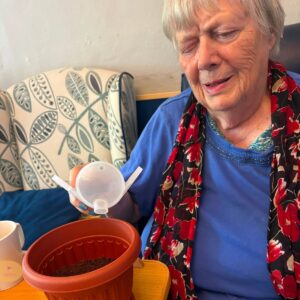 Elderly woman preparing a herb garden pot.