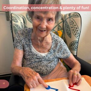 Smiling elderly woman participating in a colorful coordination activity.