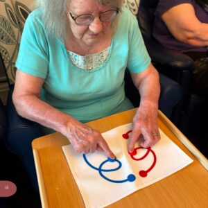 Elderly woman matching colored shapes on a tabletop activity board.