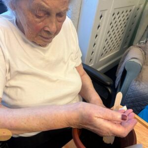 Elderly woman planting seeds in a pot.
