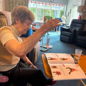 Elderly woman raising her arms during chair yoga.