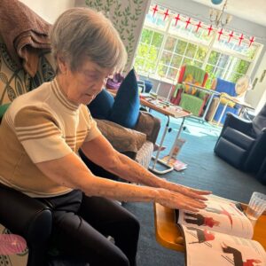Elderly woman stretching forward during chair yoga.