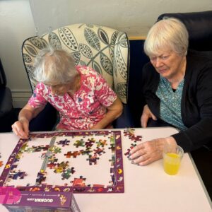 Two women focused on completing a puzzle together.