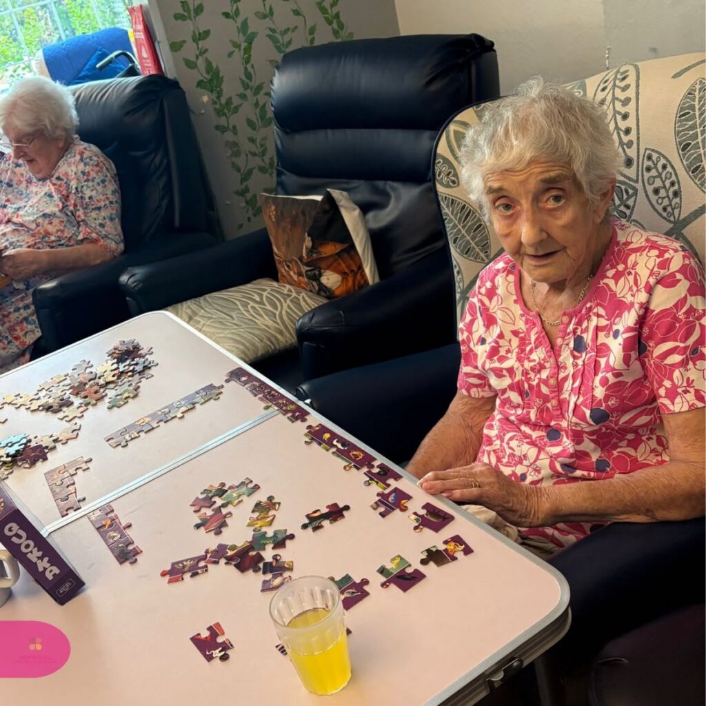 Two elderly women working on a jigsaw puzzle.