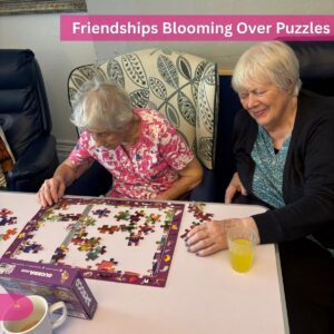 Two elderly women smiling while doing a jigsaw puzzle.