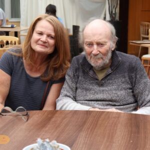 An older couple sitting together at a table during a care home visit.