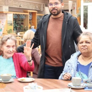 Care home residents sharing a friendly café visit with a staff member.