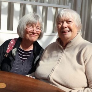 Two elderly residents smiling together while enjoying time indoors.